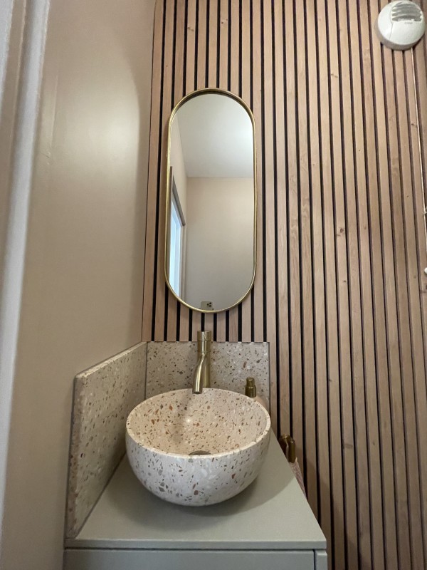 Lavabo en terrazzo et miroir doré dans un aménagement de toilette contemporain à St Cloud 92